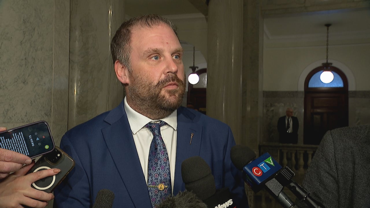 UCP MLA Brandon Lunty speaking to reporters in the hall outside the Alberta legislative chamber.