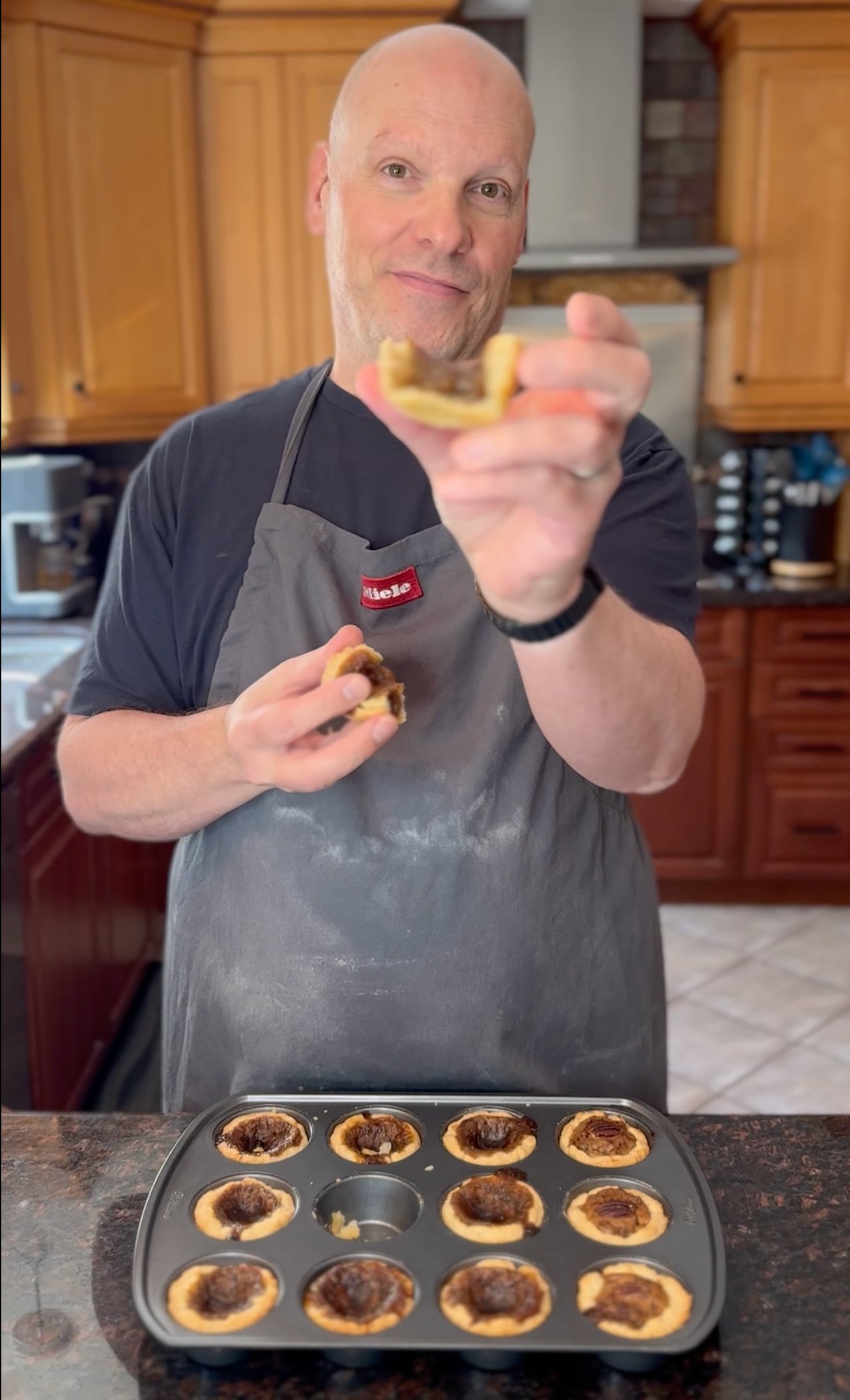 A man holds a butter tart in his hand.