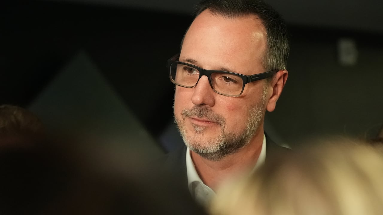 A man with glasses looks off to the side.