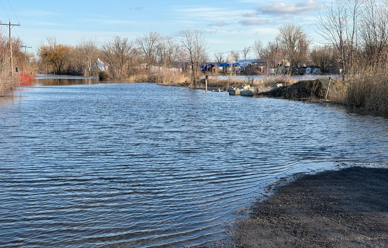 A flooded dirt road in a rural area on a spring morning.