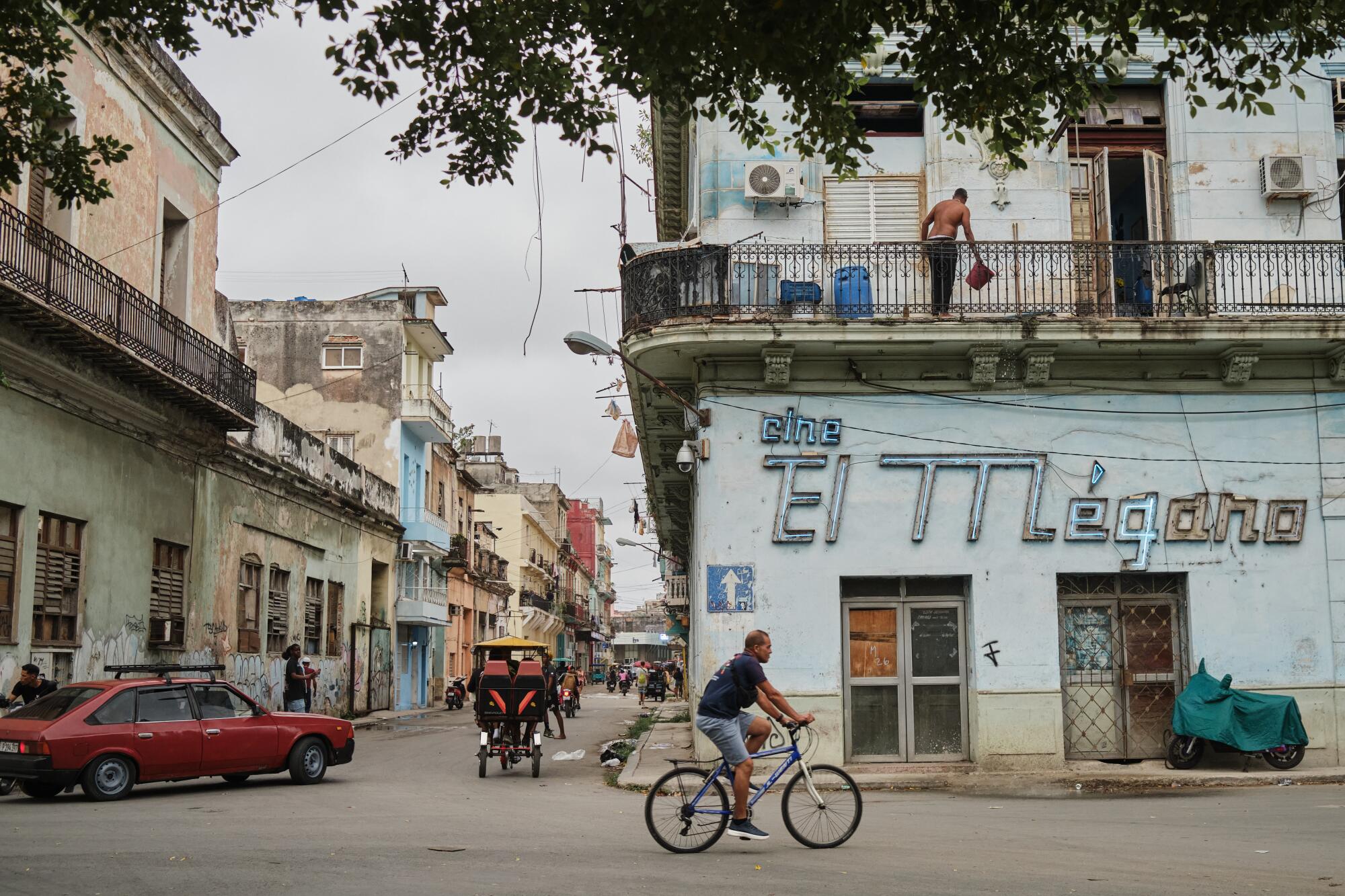 A man rides a bicycle past the former El Megano cinema in Havana.
