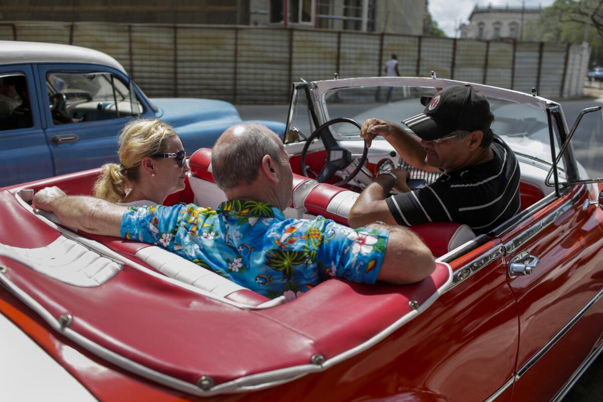 American tourists prepare for a ride around the city in a restored classic car
