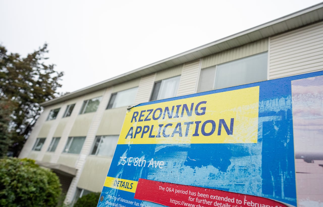 A sign outside of an apartment building that reads, 'Rezoning Application.'
