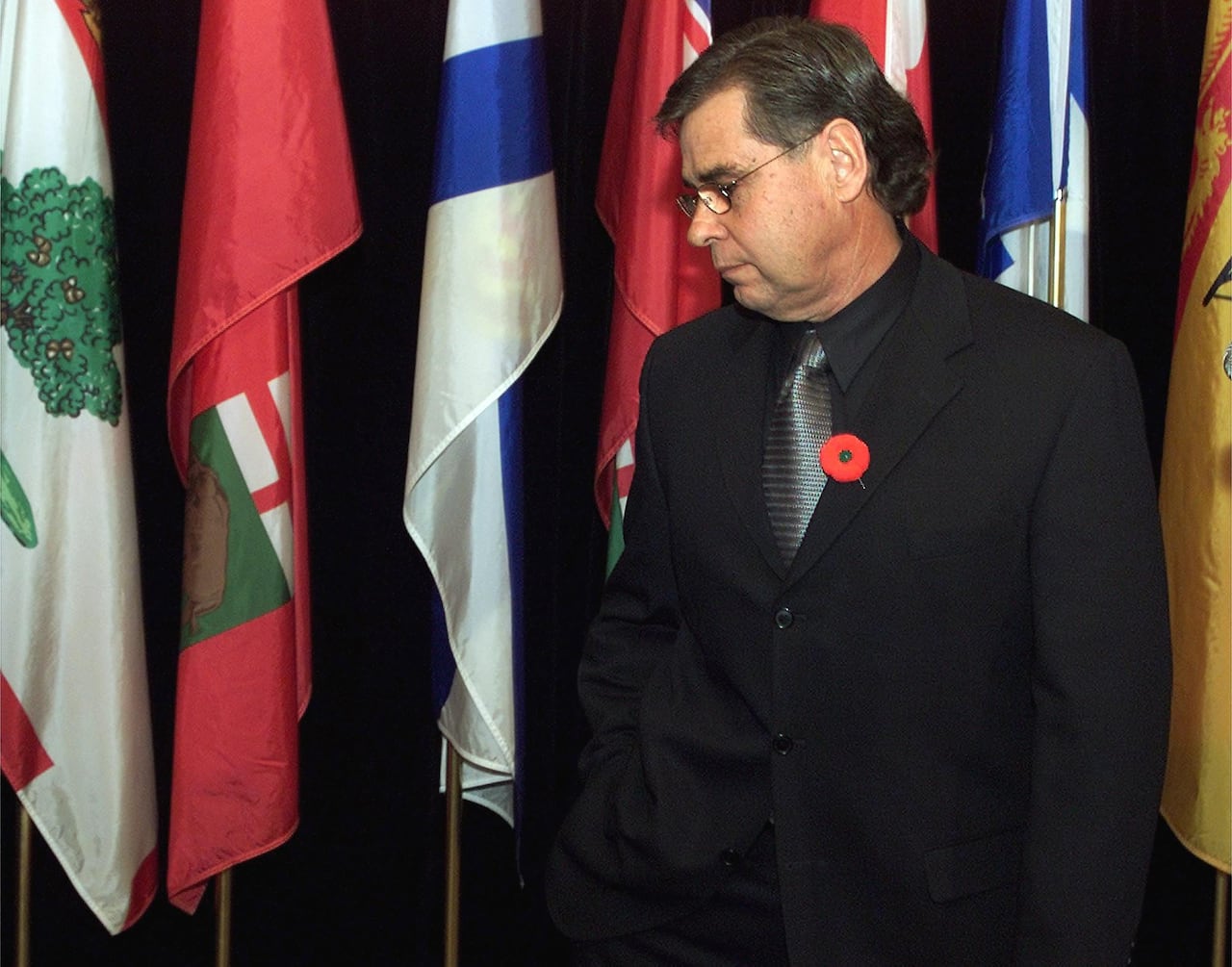 A man stands in front of a series of flags.