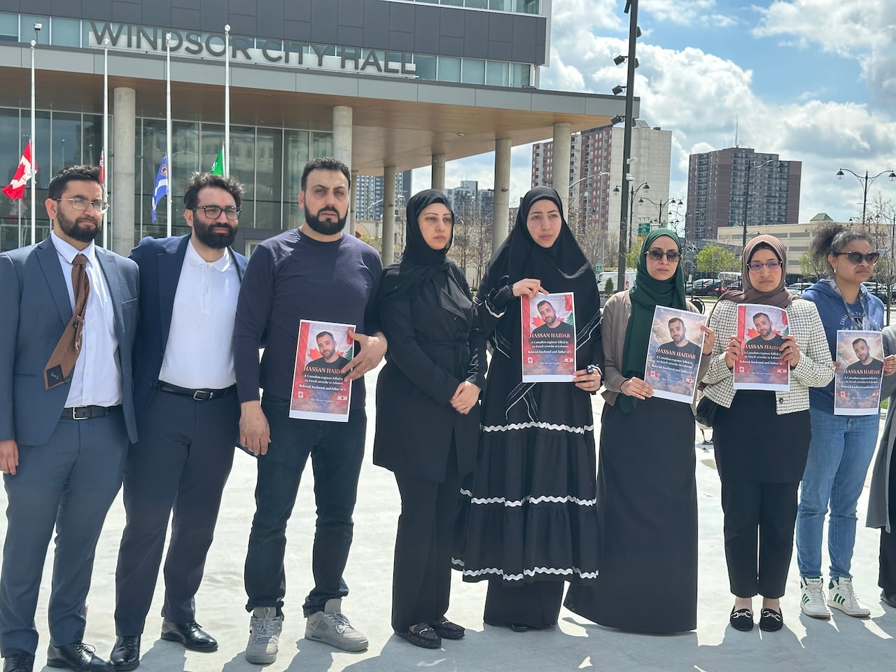 Haidar's family and friends hold up signs mourning killed Canadian