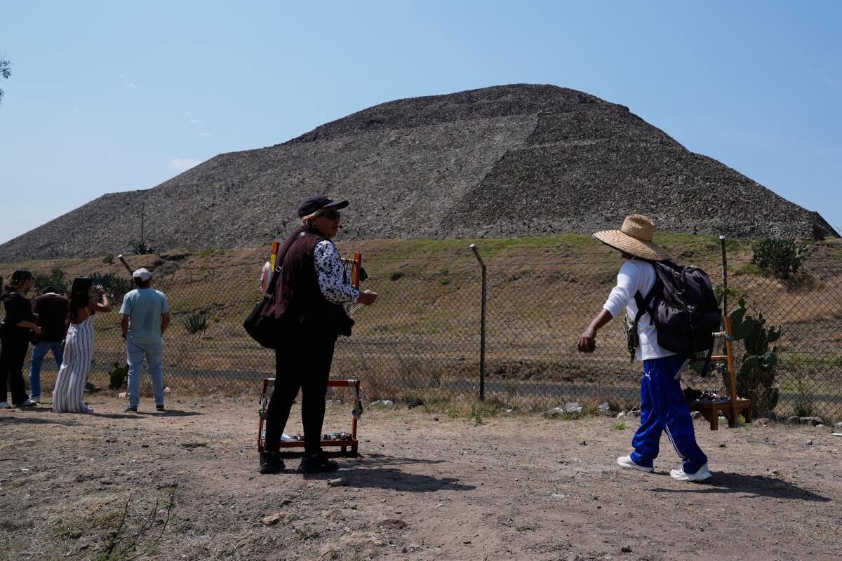 Handicraft vendors and tourists stand outside the Teotihuacán  pyramids