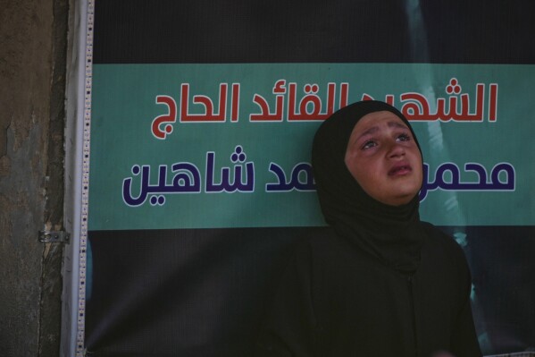 A girl mourns during a mass funeral procession for Hezbollah fighters killed before the ceasefire in the war between Hezbollah and Israel in the southern village of Kfar Sir, Lebanon, Tuesday, April 21, 2026. (AP Photo/Hassan Ammar)