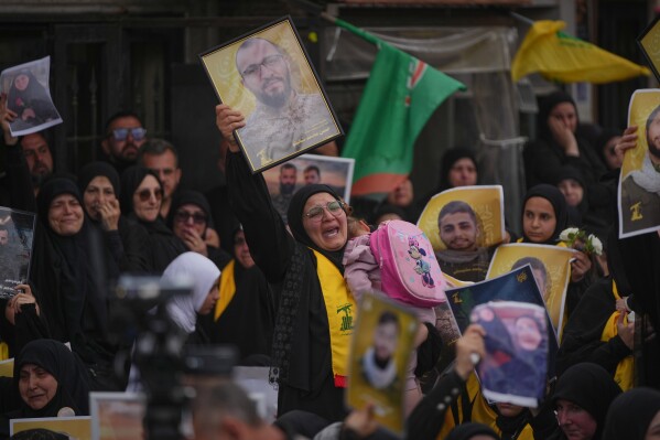 A woman mourns while holding a portrait of a Hezbollah fighter killed before the ceasefire in the war between Hezbollah and Israel during a mass funeral procession in the southern village of Kfar Sir, Lebanon, Tuesday, April 21, 2026. (AP Photo/Hassan Ammar)