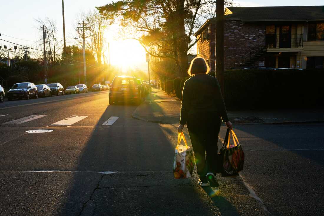 A woman carries reusable shopping bags to her car on Monday, March 16, 2026, in Portland, Ore.