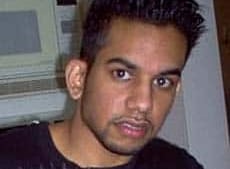 A man with spikey dark hair, wearing a black T-shirt.