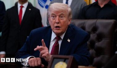 Trump points his finger as he speaks in the Oval Office with his supporters standing behind him