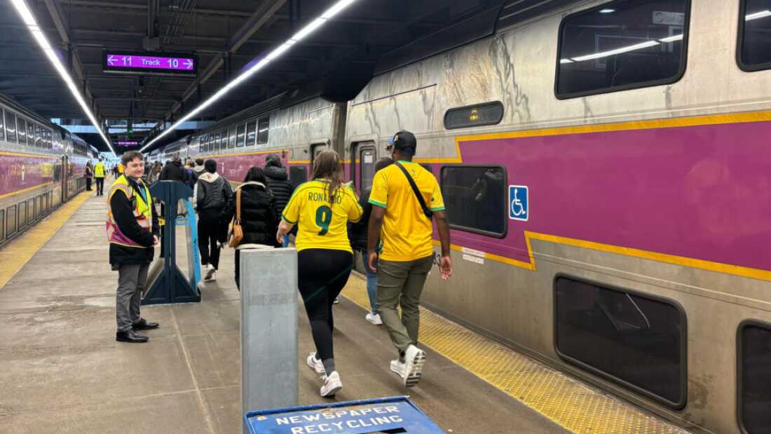 Fans in Brazil jerseys walk down the platform at South Station to board an event train headed for Gillette Stadium.