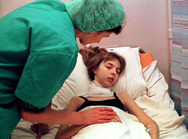 A medical worker attends to a 17-year-old girl recovering from surgery to remove her cancerous thyroid at the intensive therapy unit of the Endocrynology Institute in Kyiv, Ukraine, Nov. 30, 2000, nearly 15 years after the explosion and fire at the Chernobyl nuclear power plant. (AP Photo/Efrem Lukatsky, File)
