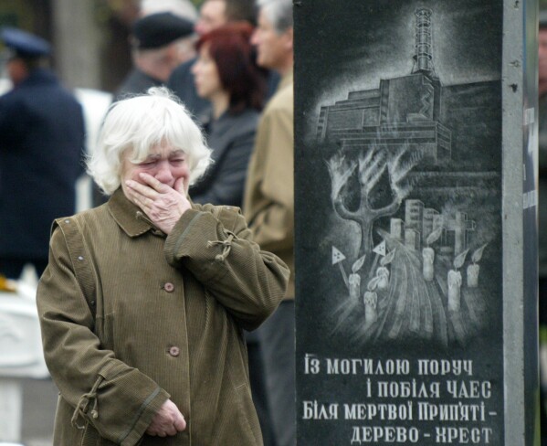 Alehandra Lihova, sister of a worker who died following cleanup operations from the 1986 explosion and fire at the Chernobyl nuclear power plant, wipes away tears at a wreath-laying ceremony at a monument to victims in Kyiv, Ukraine, April 26, 2004. The monument depicts the plant and its inscription reads "Near the grave, near the Chernobyl nuclear power station, near the dead Prypiat, a tree is the cross." (AP Photo/Efrem Lukatsky, File)