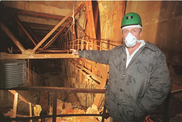 An investigator points toward damaged Reactor No. 4 inside the Chernobyl nuclear power plant in Chernobyl, Ukraine, Nov. 10, 2000. (AP Photo/Efrem Lukatsky, File)