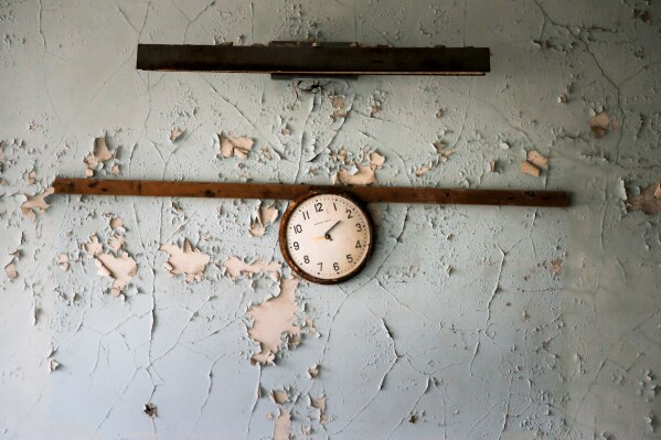 A broken clock hangs on a wall in a school in the deserted town of Pripyat, Ukraine, April 5, 2017, once home to people whose lives were connected to the Chernobyl nuclear power plant about 3 kilometers (nearly 2 miles) away. (AP Photo/Efrem Lukatsky, File)
