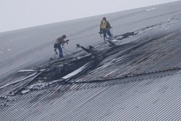 Workers examine the damage to the roof of the New Safe Confinement structure, which was built to contain the radioactive remains of Reactor No. 4 at the Chernobyl nuclear power plant, following what Ukrainian officials said was a Russian drone attack in Chernobyl, Ukraine, Feb. 14, 2025. (AP Photo/Efrem Lukatsky, File)