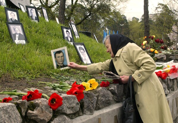 Praskoviya Nezhyvova places a photo of her son, Viktor, who died following cleanup operations from the 1986 Chernobyl nuclear plant accident, at a monument to the victims in Kyiv, April 26, 2004. (AP Photo/Efrem Lukatsky, File)