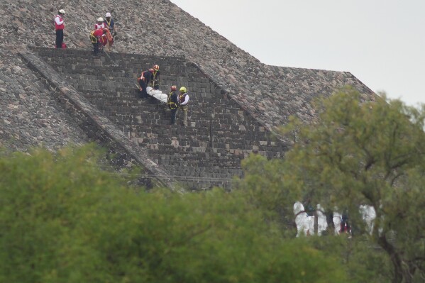 Forensic workers carry the body of a victim down a pyramid after authorities said a gunman opened fire, in Teotihuacan, Mexico, Monday, April 20, 2026. (AP Photo/Eduardo Verdugo)