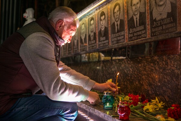 A man lights a candle at a memorial dedicated to firefighters and workers who died after the 1986 Chornobyl (Chernobyl) nuclear disaster, ahead of its 40th anniversary in Slavutych, Ukraine, Saturday, April 25, 2026. Chornobyl is the Ukrainian name for the city. (AP Photo/Dan Bashakov)