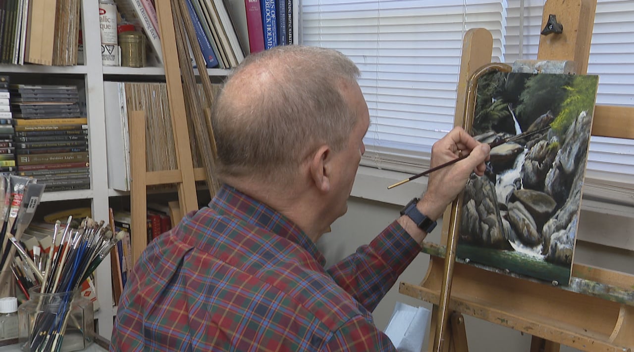 Bruce Newman working on a painting of al waterfall near Fredericton.
