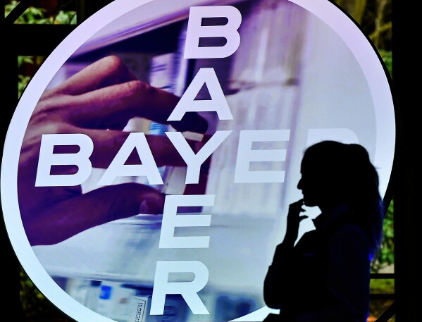 A woman walks in front of a logo of Bayer AG at the Financial News Conference in Leverkusen, Germany, Feb. 27, 2020. (AP Photo/Martin Meissner, File)