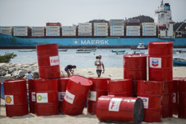A family walks near a Make Polluters Pay demonstration along the Caribbean Sea demanding oil companies pay for the energy transition during a nearby conference aimed at transitioning away from fossil fuels Monday, April 27, 2026, in Santa Marta, Colombia. (AP Photo/Ivan Valencia)