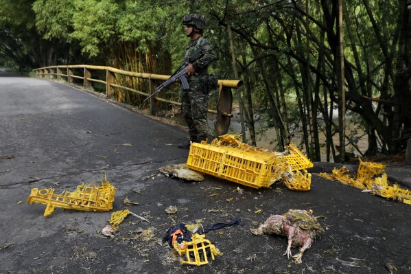 Soldiers stand next to a truck carrying chickens that was set on fire by dissident factions of the former FARC rebels in Jamundi, Colombia, Monday, April 27, 2026. (AP Photo/Santiago Saldarriaga)