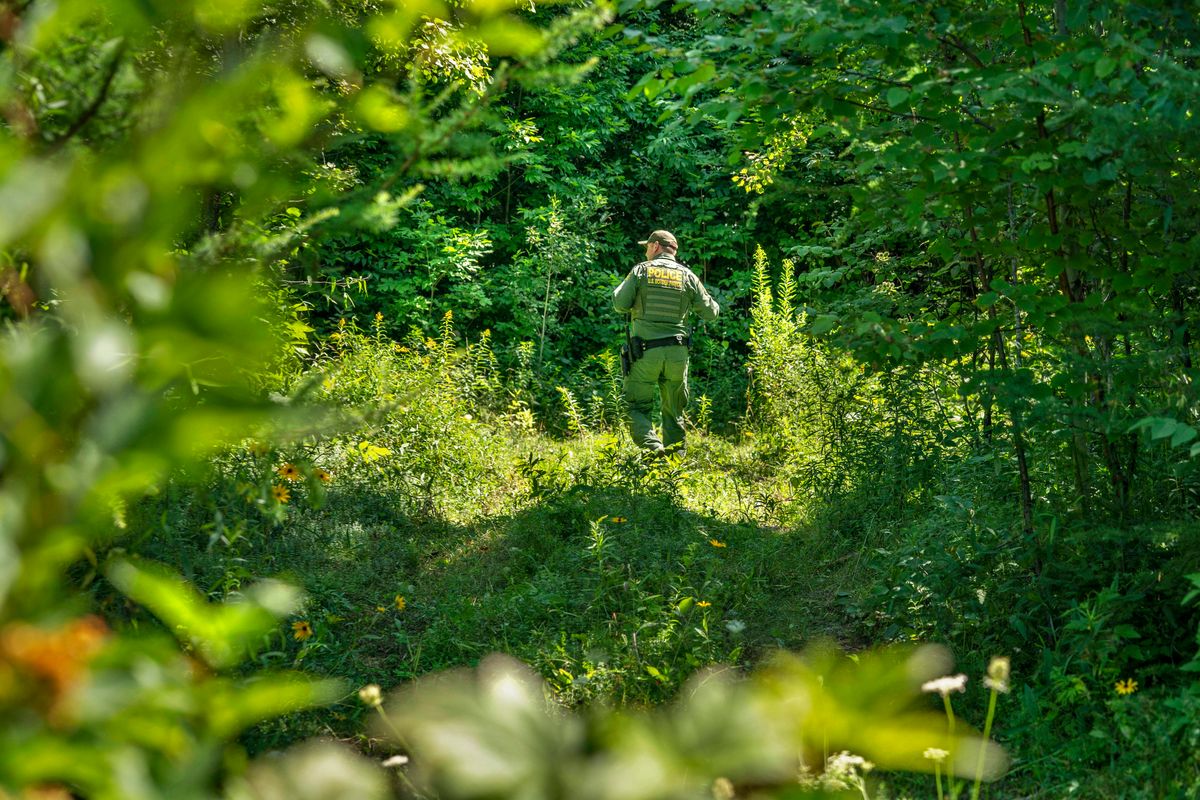 A U.S. Border Patrol agent walks through the woods along the border of Canada and the United States in Houlton, Maine