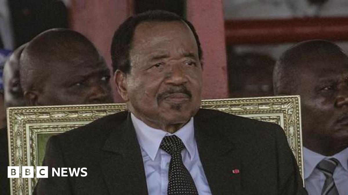 Paul Biya wearing a dark suit and tie sitting in a gold-backed chair.