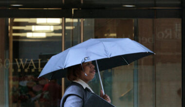 FILE PHOTO: A woman walks through the rain on Wall Street in New York