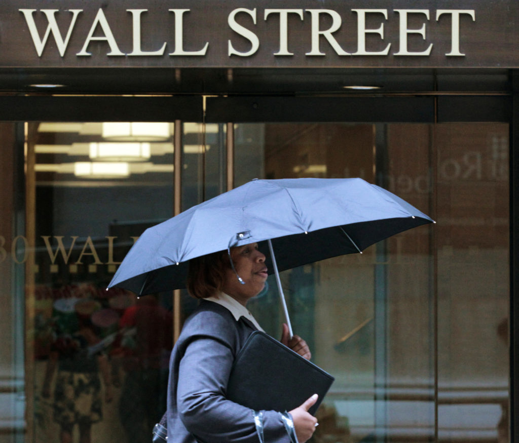 FILE PHOTO: A woman walks through the rain on Wall Street in New York