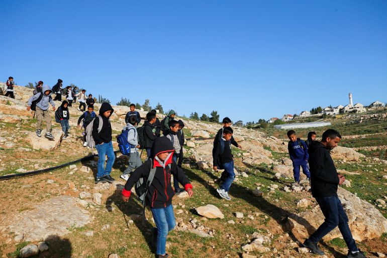 Palestinian students gather near a fence installed by Israeli settlers