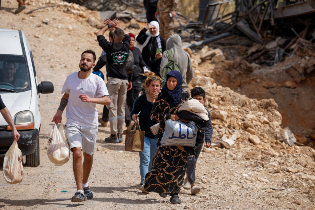 Displaced people cross the bridge linking southern Lebanon to the rest of the country, which was hit earlier in an Israeli...