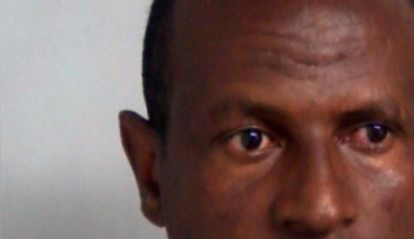 A custody photo of Hadush Kebatu, who is wearing a grey sweater and has cropped black hair.