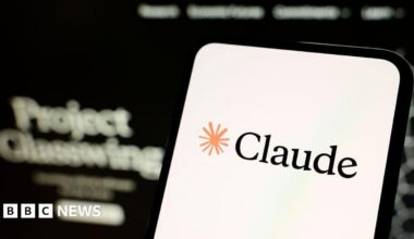 A smartphone screen displaying the name Claude and a drawing of an asterisk. Out of focus in the background the words Project Glasswing are legible.