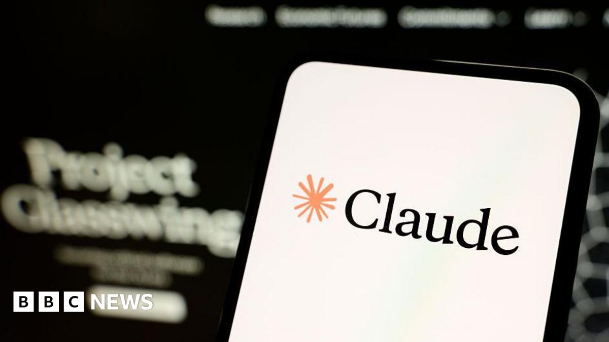 A smartphone screen displaying the name Claude and a drawing of an asterisk. Out of focus in the background the words Project Glasswing are legible.