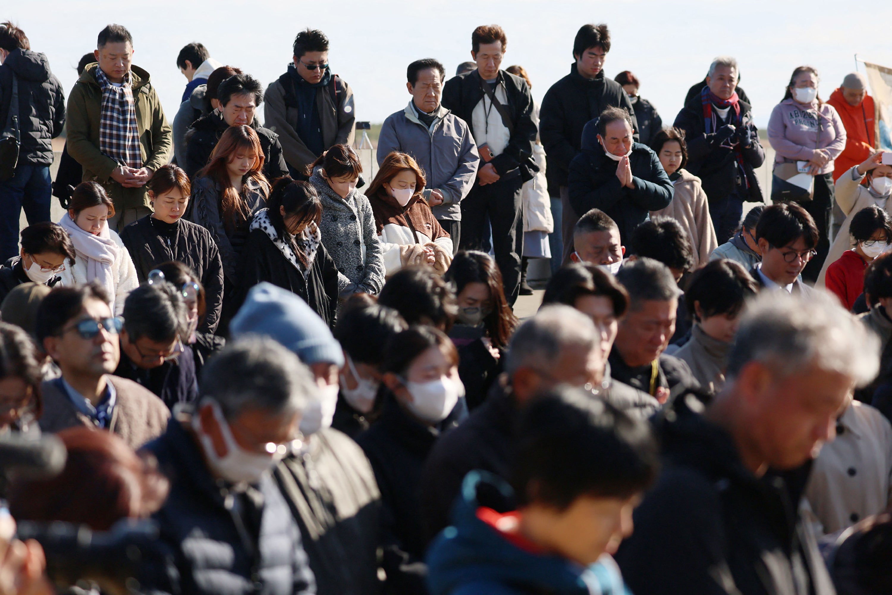 People pray silently at the time of the Great East Japan earthquake, 2.46pm in Natori City, Miyagi prefecture on the 15th anniversary of the 2011 earthquake and tsunami disaster