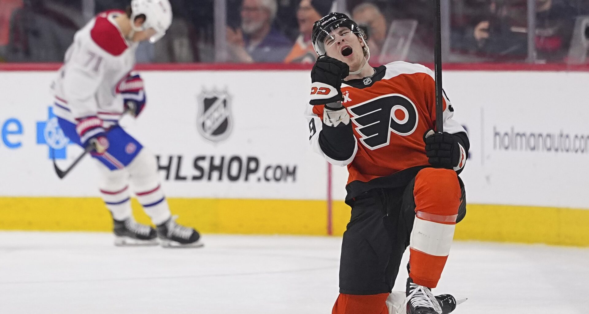 Flyers' Oliver Bonk celebrates on one knee on the ice while a Canadiens player in the background looks down at his feet.