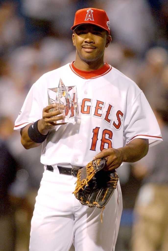 Baseball player Garret Anderson holding an MVP trophy and baseball glove.