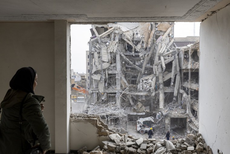A woman looks out upon residential buildings that were destroyed a few days ago