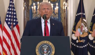 A man in business attire speaks from behind a lectern.