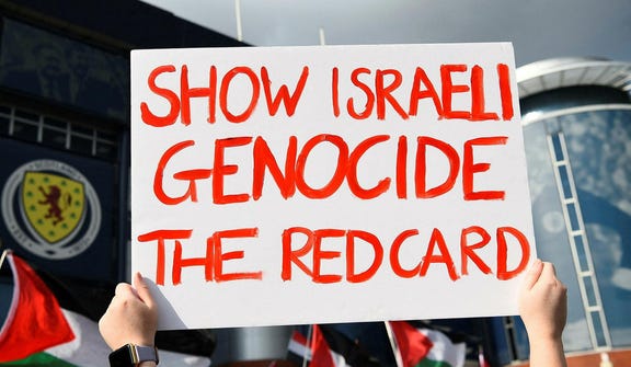 An anti-Israel demonstrator holds a placard at an Israel-Scotland soccer match in Glasgow, Scotland, in 2024.