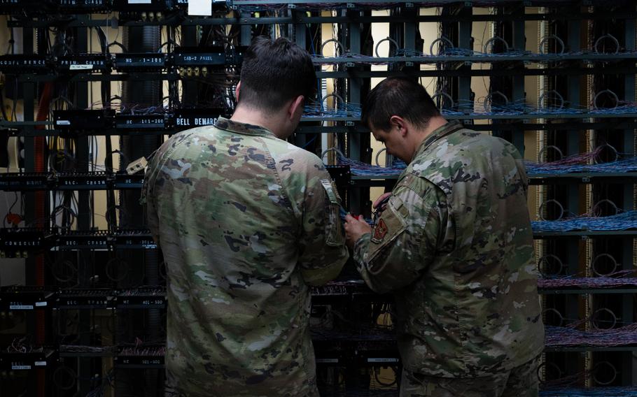 Two service members are working on a telephone line board.