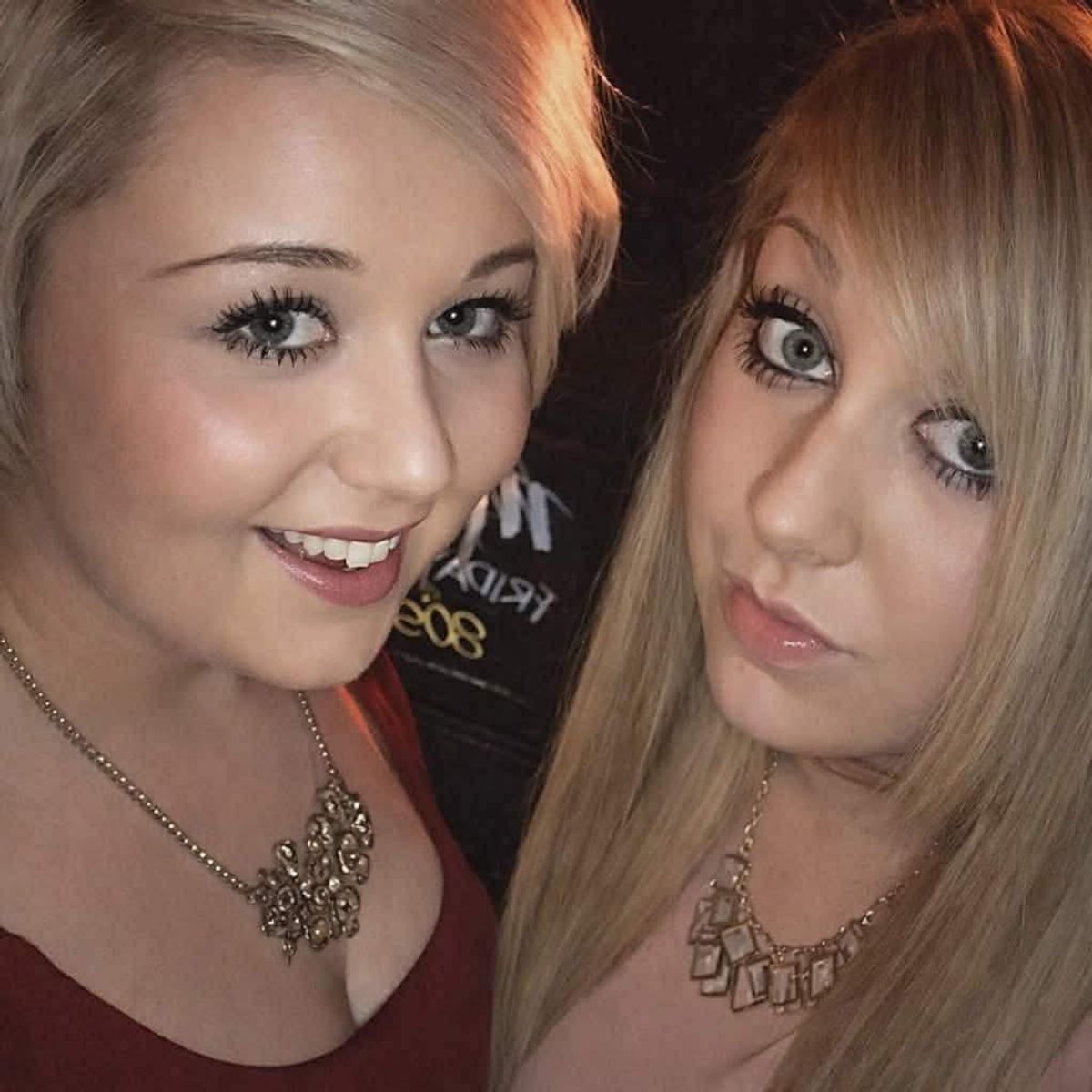 Two sisters in their early 20s, with long hair, smiling