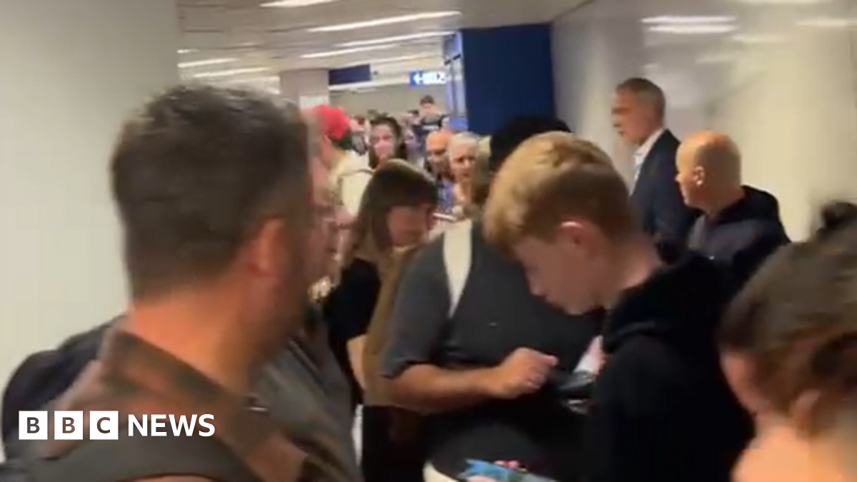 Image shows long queues of people at Milan airport.