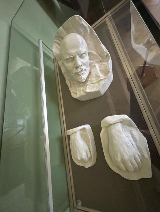 Museum display of historical plaster casts: a face and two hands. Likely part of an exhibit on notable figures or preservation techniques