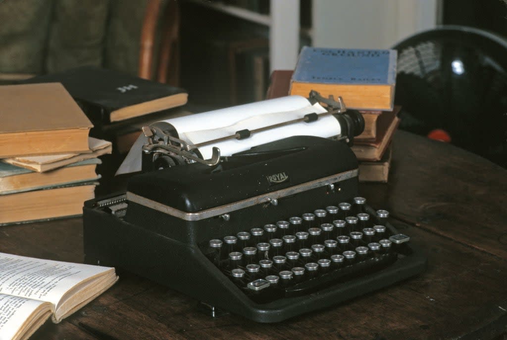 Vintage typewriter on a wooden desk surrounded by open and closed books