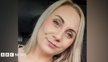 Allison Rowe who has short greying hair with pursed lips and wearing maroon rimmed round glasses and a denim top