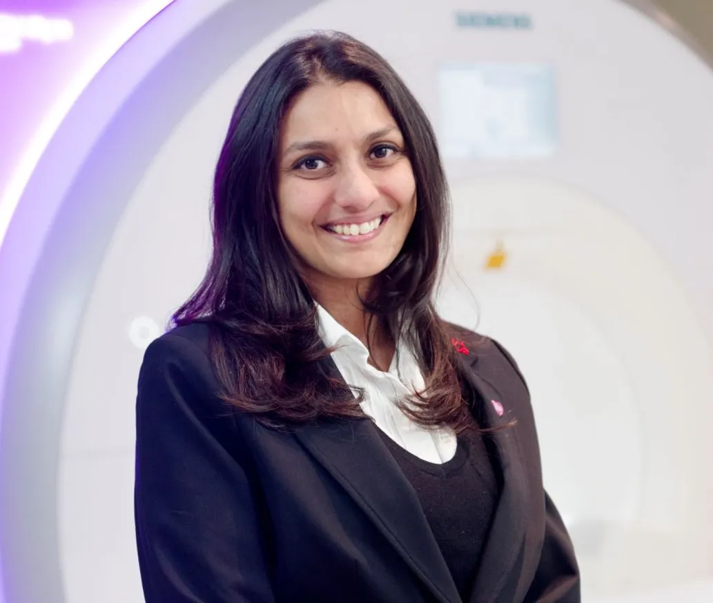 Dr. Sonya Babu-Narayan, Consultant Cardiologist, smiling in front of a medical imaging machine.